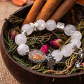 White and Garden Phantom Quartz bracelet with Magic Box centerpiece, silver accents, resting on herbs and dried flowers in wooden bowl