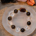 Earthbound Light Bracelet with 12mm round smoky quartz, clear quartz beads, and a natural wood focal bead on fabric background
