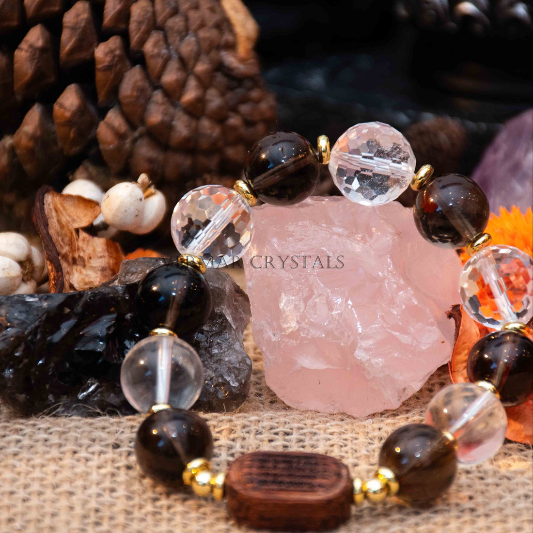 Close-up of Earthbound Light Bracelet with smoky quartz, clear quartz, and natural wood beads on burlap with crystals background