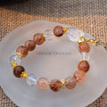 Close-up of Autumn Sunlight Bracelet with 10mm black rutilated quartz and clear quartz beads on frosted plate