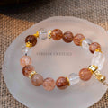 Close-up of Autumn Sunlight Bracelet with 10mm black rutilated quartz and clear quartz beads on white dish background