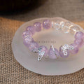 Lavender amethyst bead bracelet with silver butterfly charms displayed on frosted round dish on burlap background