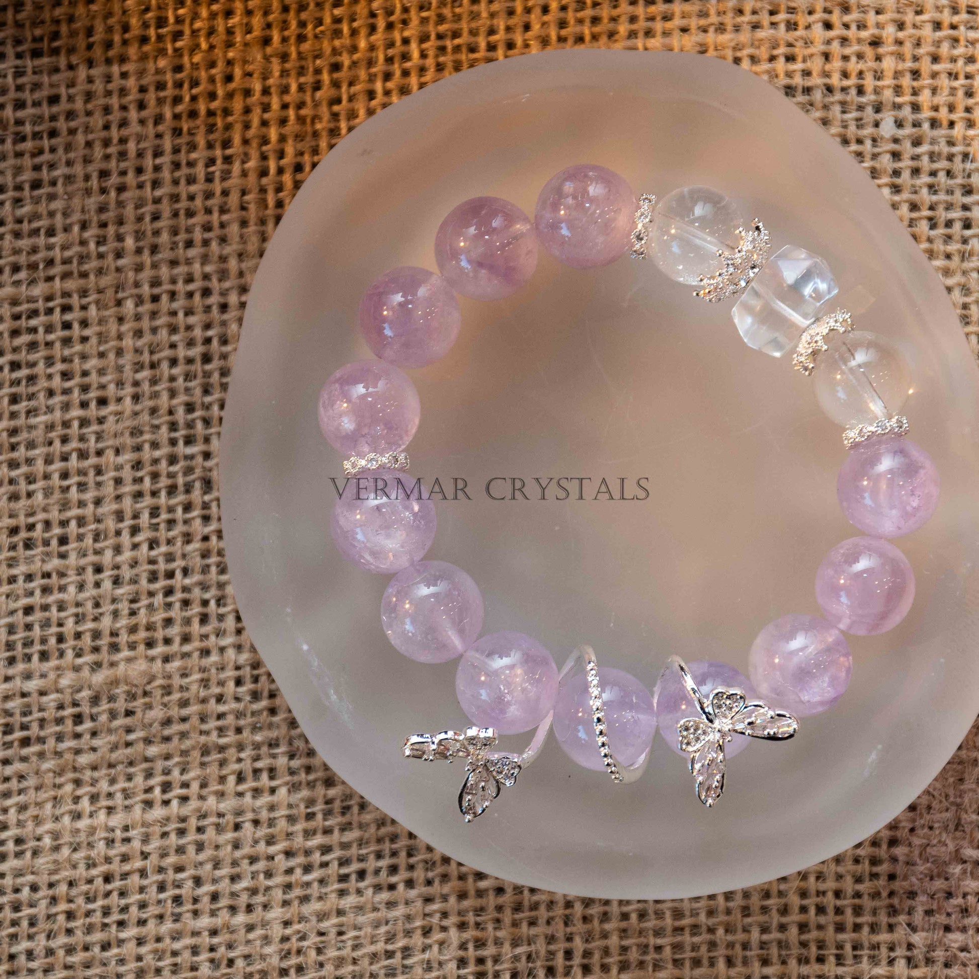 Lavender amethyst beaded bracelet with silver leaf charms resting on frosted round dish over burlap background