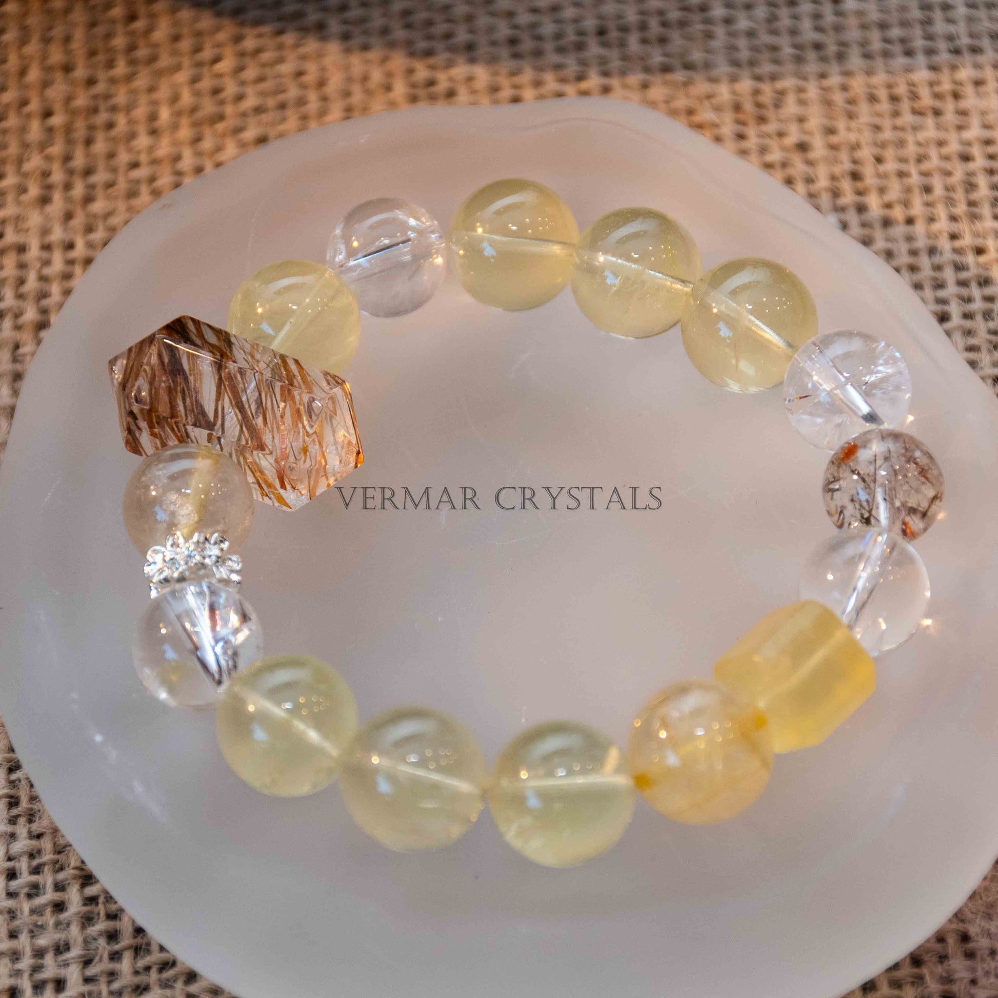 Bracelet featuring round yellow citrine and clear phantom quartz beads with a larger textured phantom quartz centerpiece on white dish
