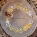 Stretch bracelet with round citrine and phantom quartz beads, featuring a rough citrine stone and decorative silver spacer on clear dish