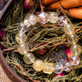 Round citrine and phantom quartz beads bracelet with silver spacer on dried greenery in wooden bowl