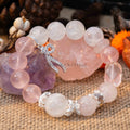 Round rose quartz and white phantom quartz beads bracelet with silver charm on natural woven surface