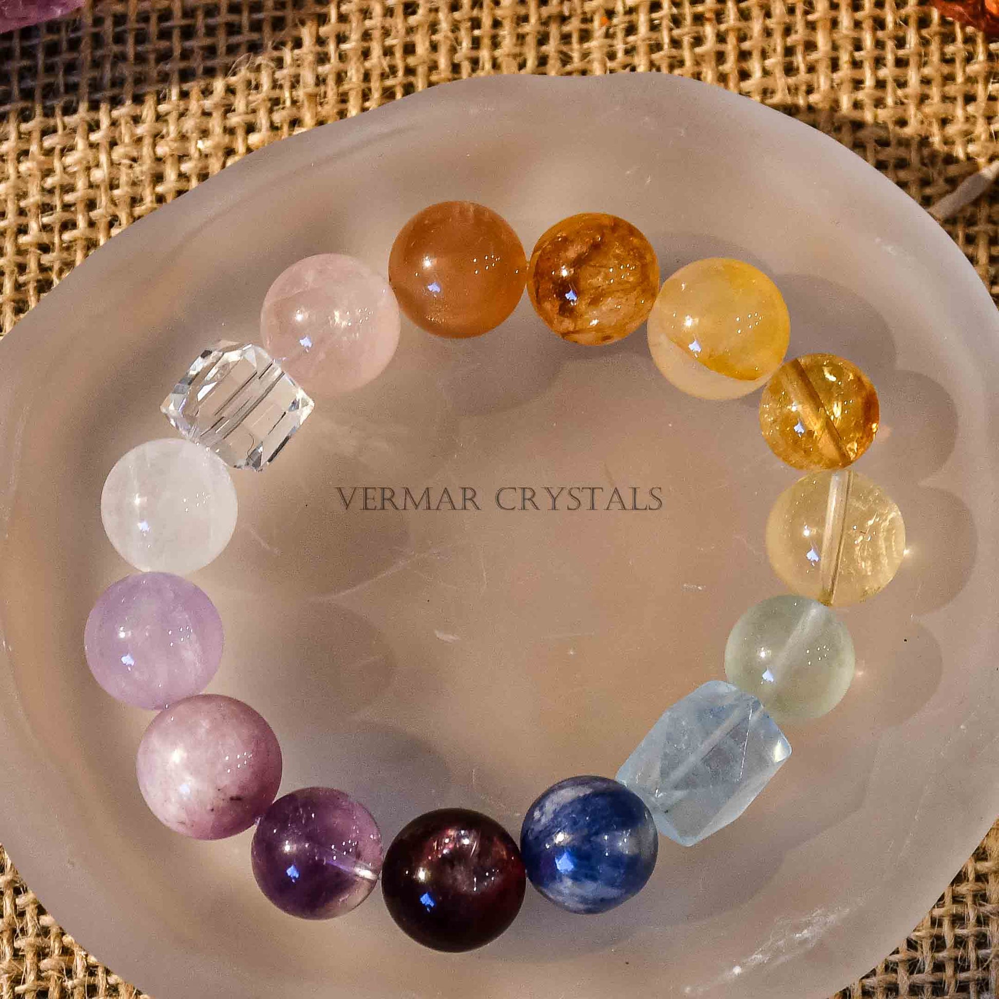 Rainbow gradient multi-gemstone bracelet with large polished beads on frosted white agate slice and burlap background