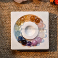 Rainbow gradient luxury multi-gemstone bracelet with large polished beads on white square ceramic dish over burlap background