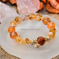 Beaded Yellow Calcite bracelet with golden spacers and a small charm resting on white agate slice on burlap background