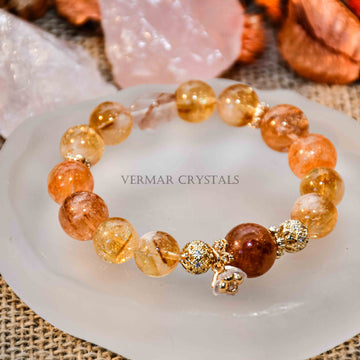 Beaded Yellow Calcite bracelet with golden spacers and a small charm resting on white agate slice on burlap background