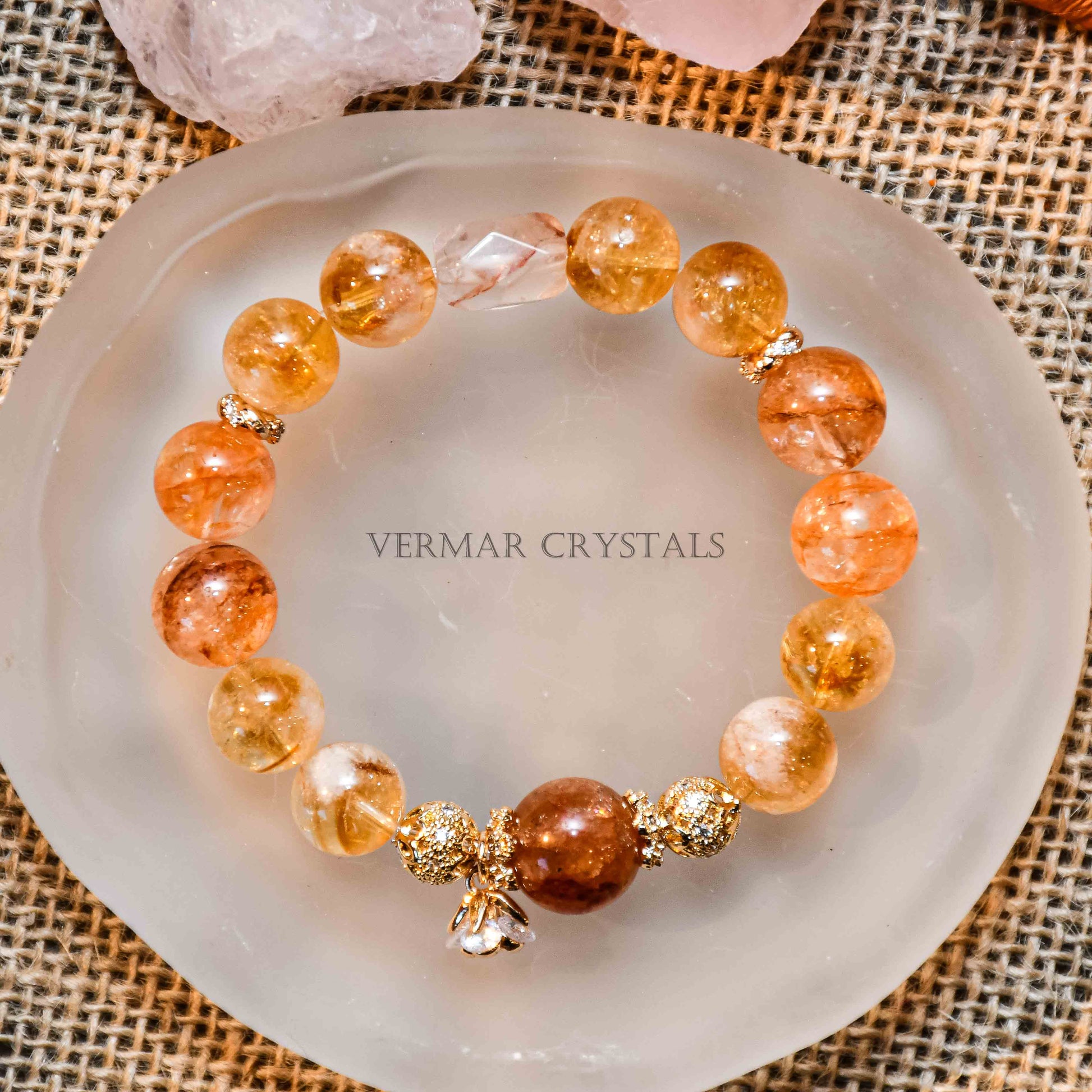 Round yellow calcite gemstone bracelet with gold accent beads and small crystal charm on frosted dish background