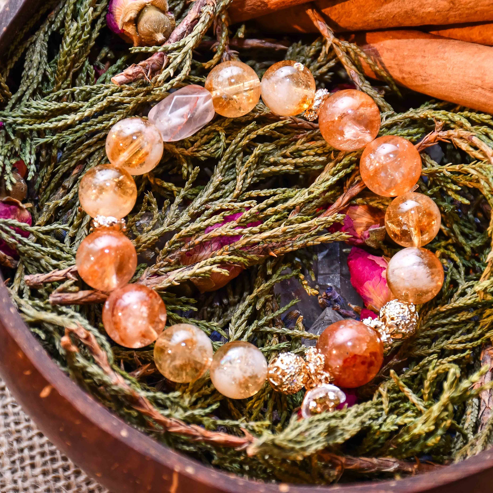 Yellow calcite beaded bracelet with gold accent beads displayed on green foliage and cinnamon sticks background