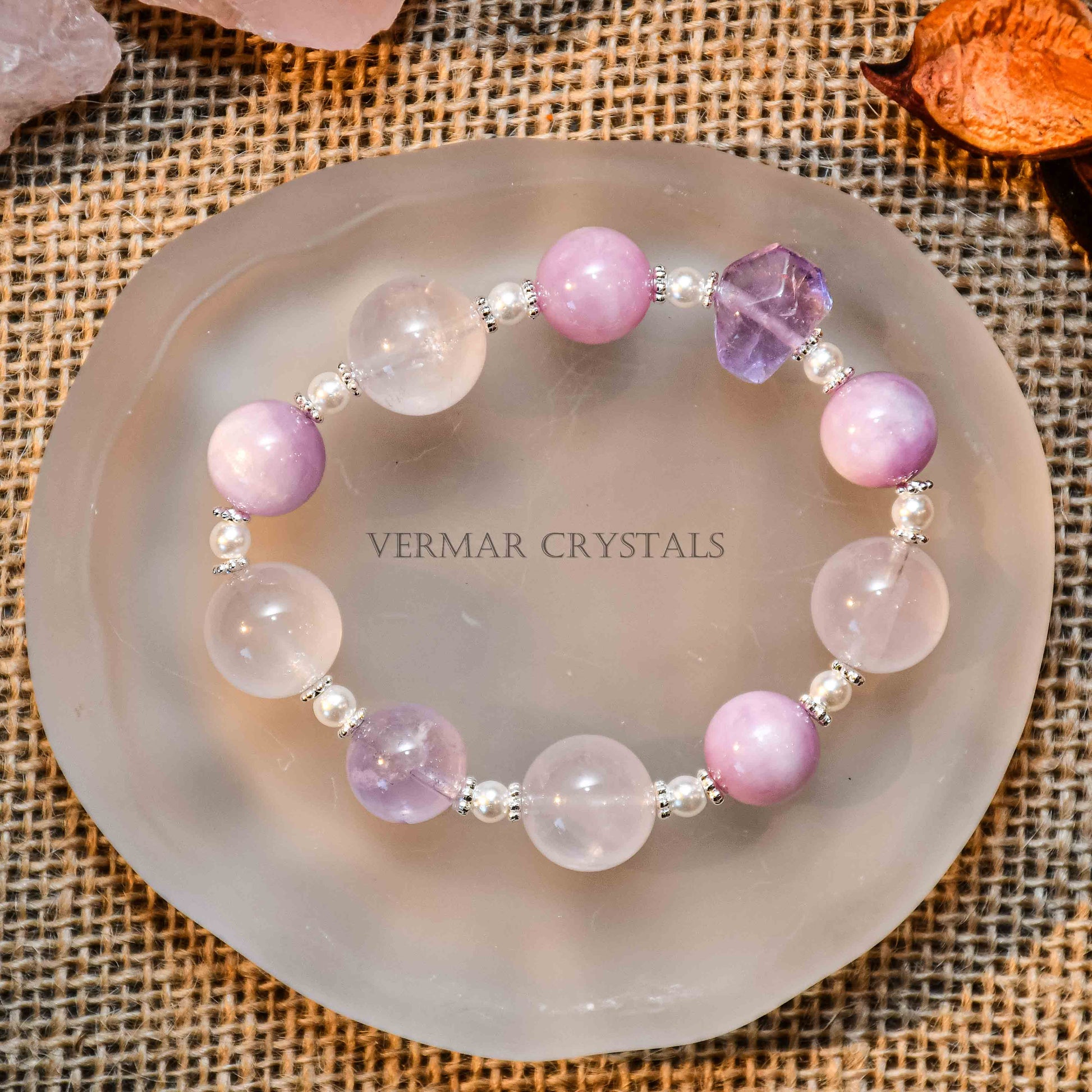 Provence Garden bracelet with round amethyst, lepidolite, and clear quartz beads on frosted agate slice background