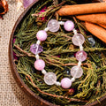 Close-up of Provence Garden bracelet with round amethyst and lepidolite beads on dried greenery and cinnamon sticks
