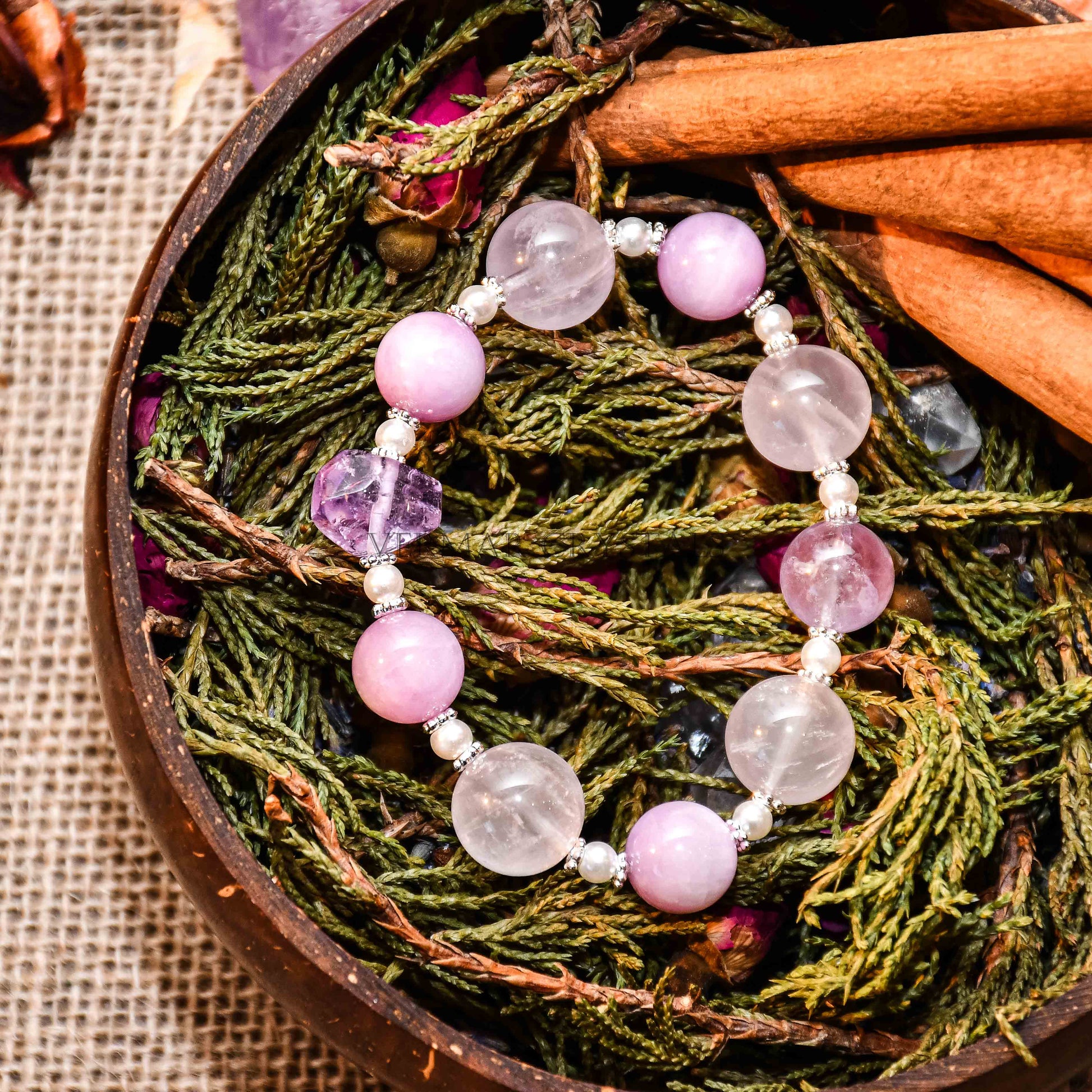 Close-up of Provence Garden bracelet with round amethyst and lepidolite beads on dried greenery and cinnamon sticks