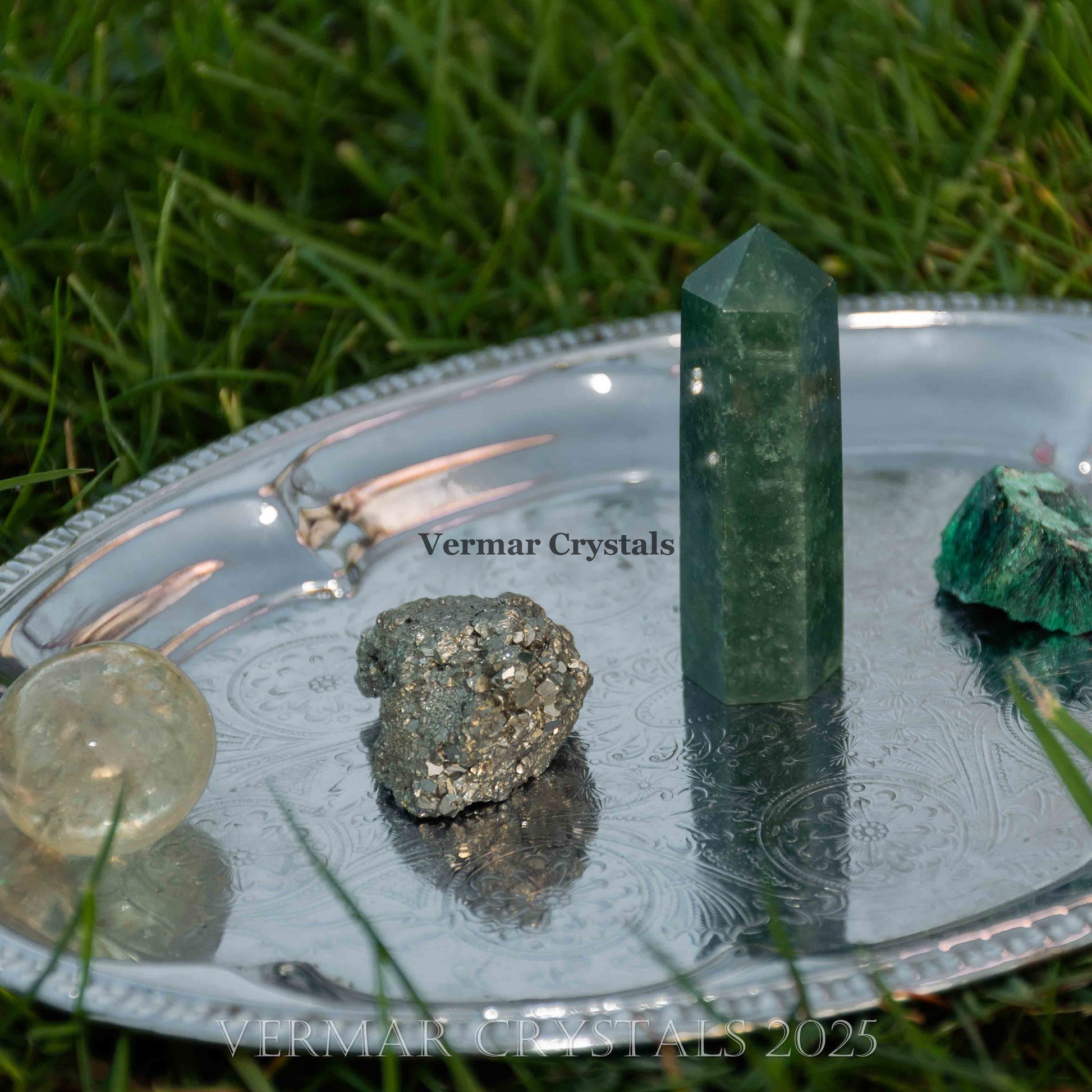 Collection of natural polished wealth and abundance crystals including green fluorite and pyrite on silver tray outdoors