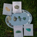 Set of four natural wealth and abundance crystals Citrine, Pyrite, Green Aventurine, and Malachite on silver tray outdoors