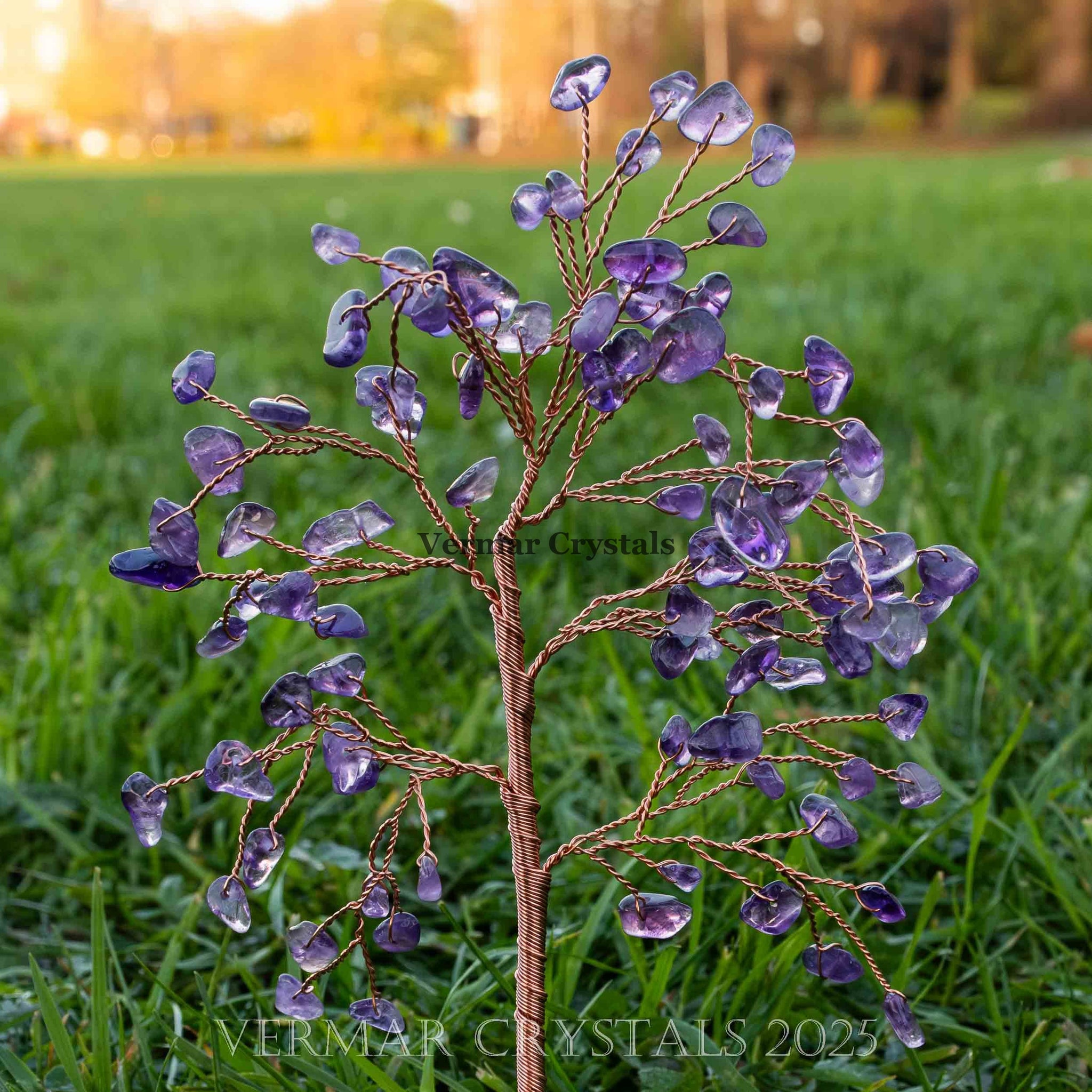 Handmade amethyst crystal tree with twisted wire branches and polished purple amethyst chips on green grass background