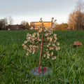 Handmade citrine crystal tree with natural yellow stones and twisted copper wire on polished agate base outdoors on grass