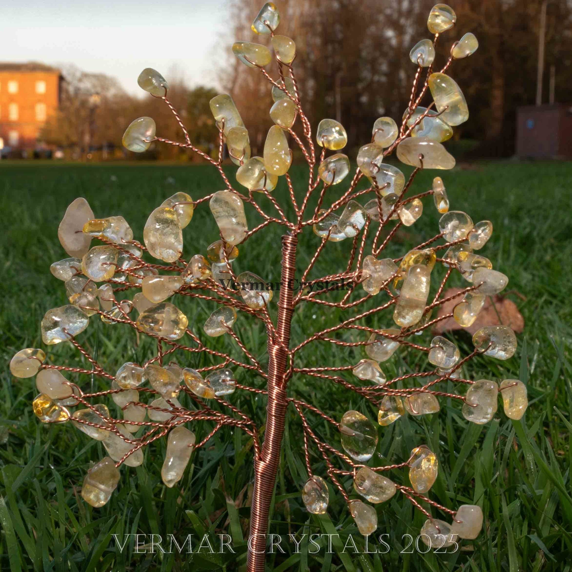 Handmade citrine crystal tree with natural yellow gemstones and twisted copper wire branches on agate base outdoors