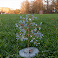 Handmade small aquamarine crystal tree with twisted copper wire branches on polished natural agate base outdoors