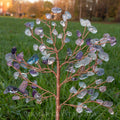 Handmade fluorite crystal tree ornament with polished agate base displayed outdoors on green grass background