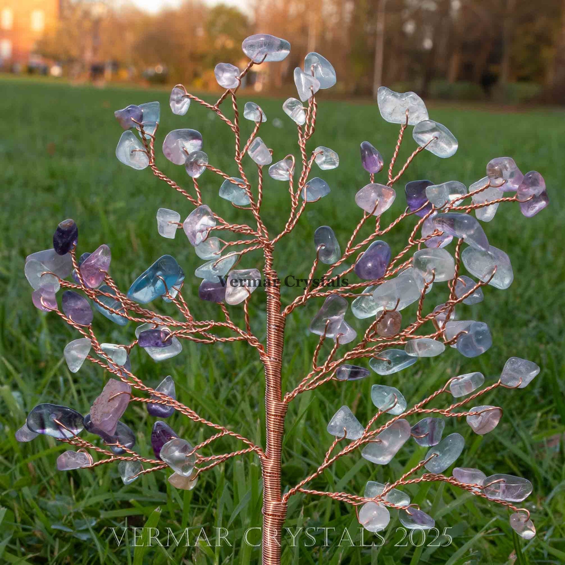 Handmade fluorite crystal tree ornament with polished agate base displayed outdoors on green grass background