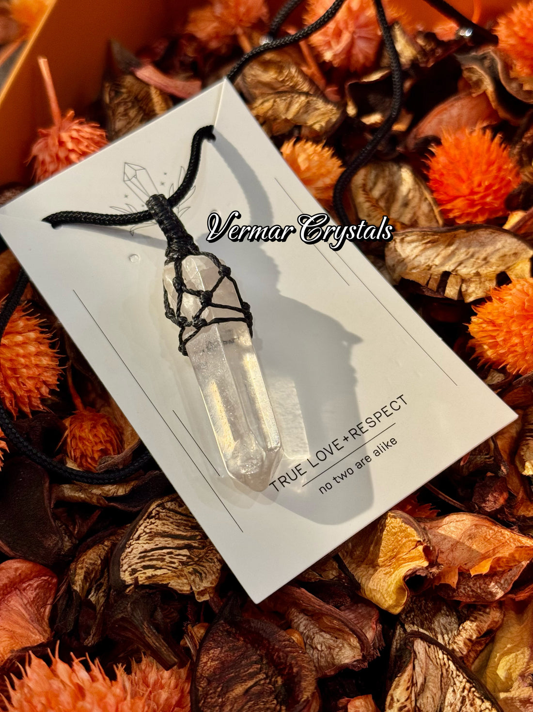 Clear quartz point pendant wrapped in black hand-woven cord on simple black necklace against light background