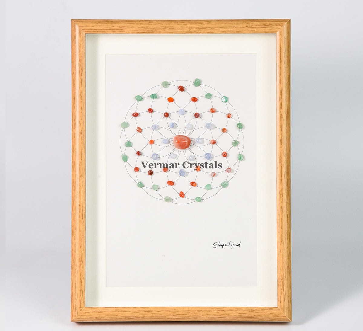 Health & Healing crystal grid art with green aventurine, red and blue agate stones in wooden frame on gray background