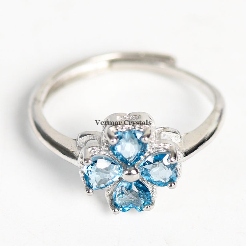 Silver ring with four heart-shaped blue gemstones forming a four-petal flower on white background