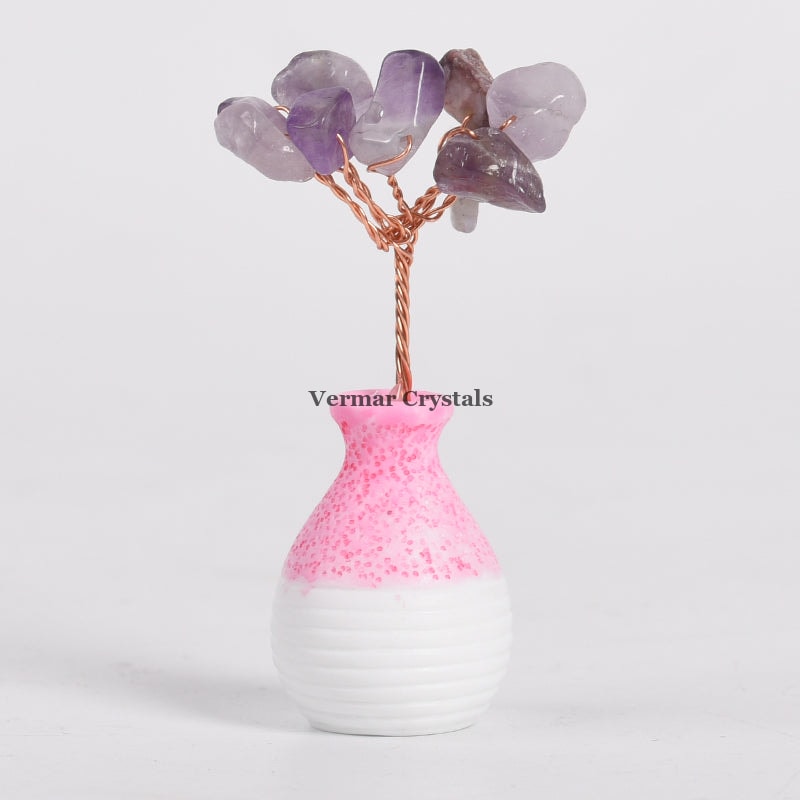 Small amethyst crystal tree ornament with copper wire branches in a pink and white ceramic vase against white background