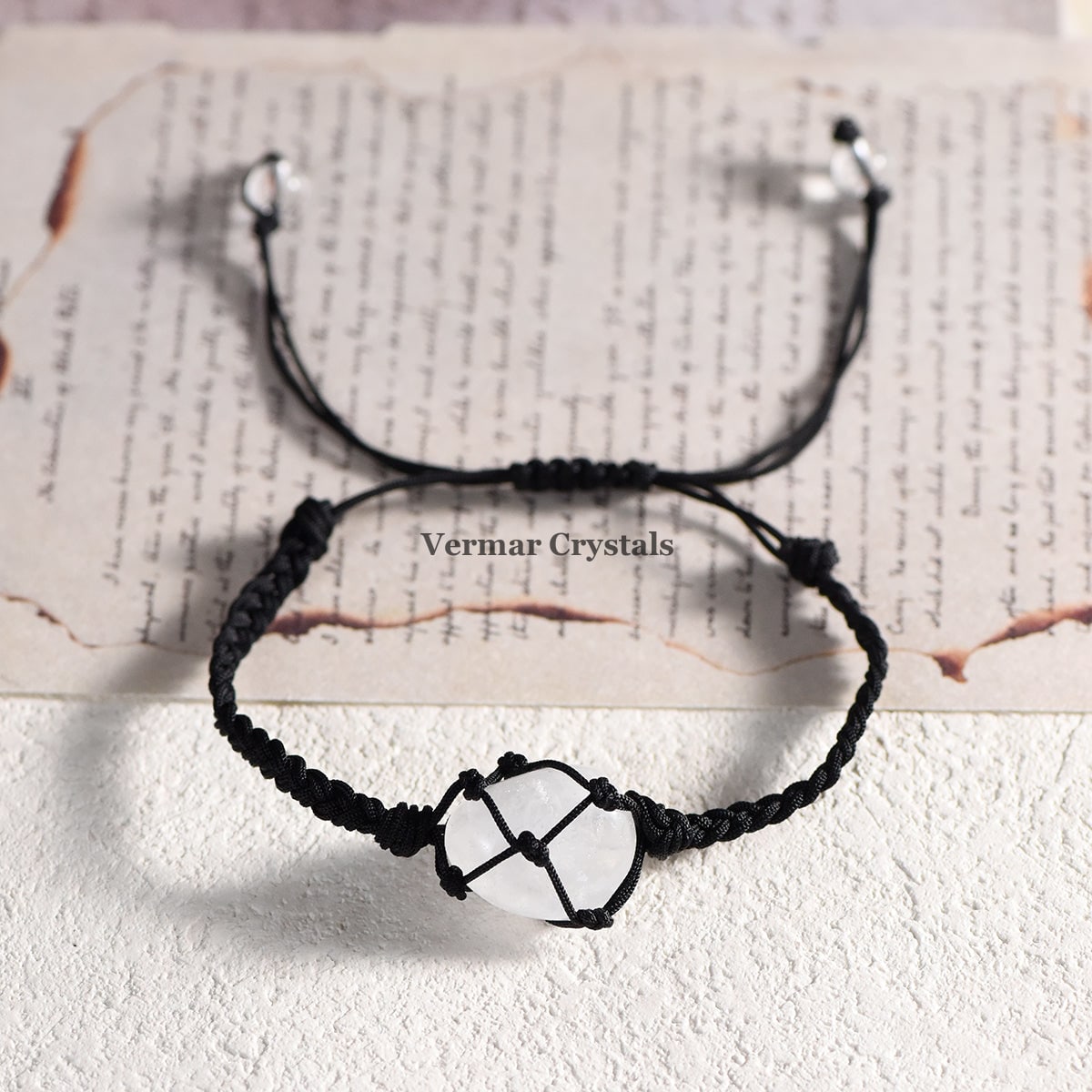 Handmade clear quartz stone secured in a black net-wrapped adjustable bracelet on a textured background