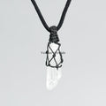 Clear quartz point pendant wrapped in black hand-woven cord on simple black necklace against light background