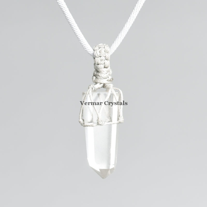 Raw clear quartz point pendant wrapped in white macramé cord on light gray background