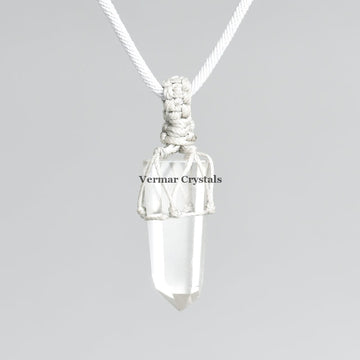 Raw clear quartz point pendant wrapped in white macramé cord on light gray background