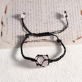 Handmade bracelet with a natural tumbled rose quartz stone wrapped in black macrame cord on a white surface