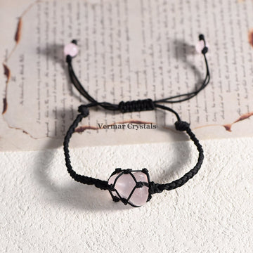 Handmade bracelet with a natural tumbled rose quartz stone wrapped in black macrame cord on a white surface