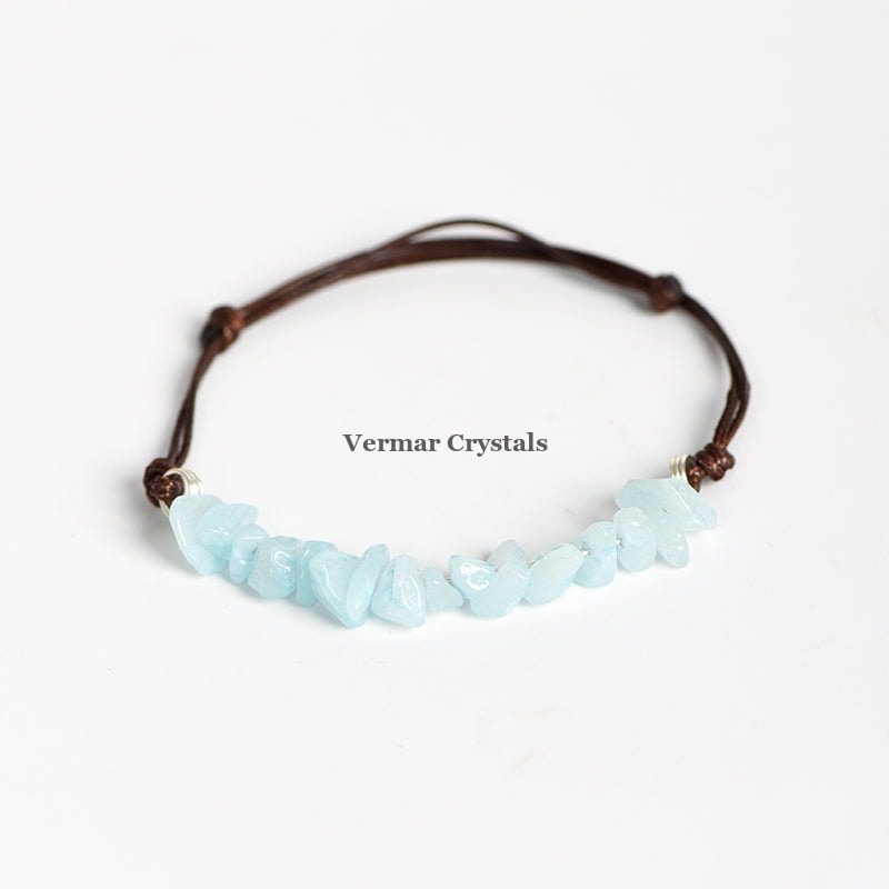 Handmade bracelet with light blue aquamarine chip stones on a brown adjustable leather cord on white background