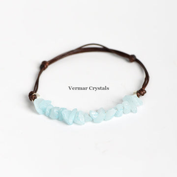 Handmade bracelet with light blue aquamarine chip stones on a brown adjustable leather cord on white background