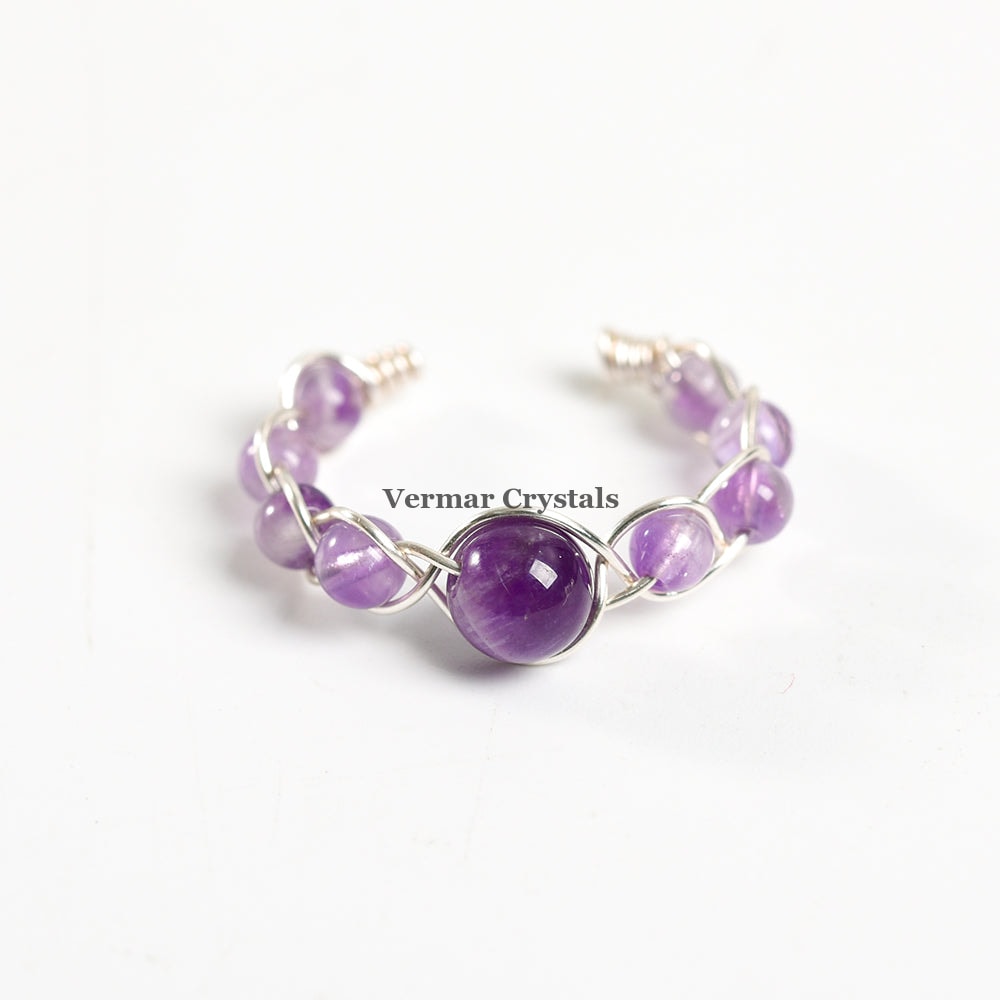Handmade adjustable amethyst braided ring with polished round and oval purple stones on a white background