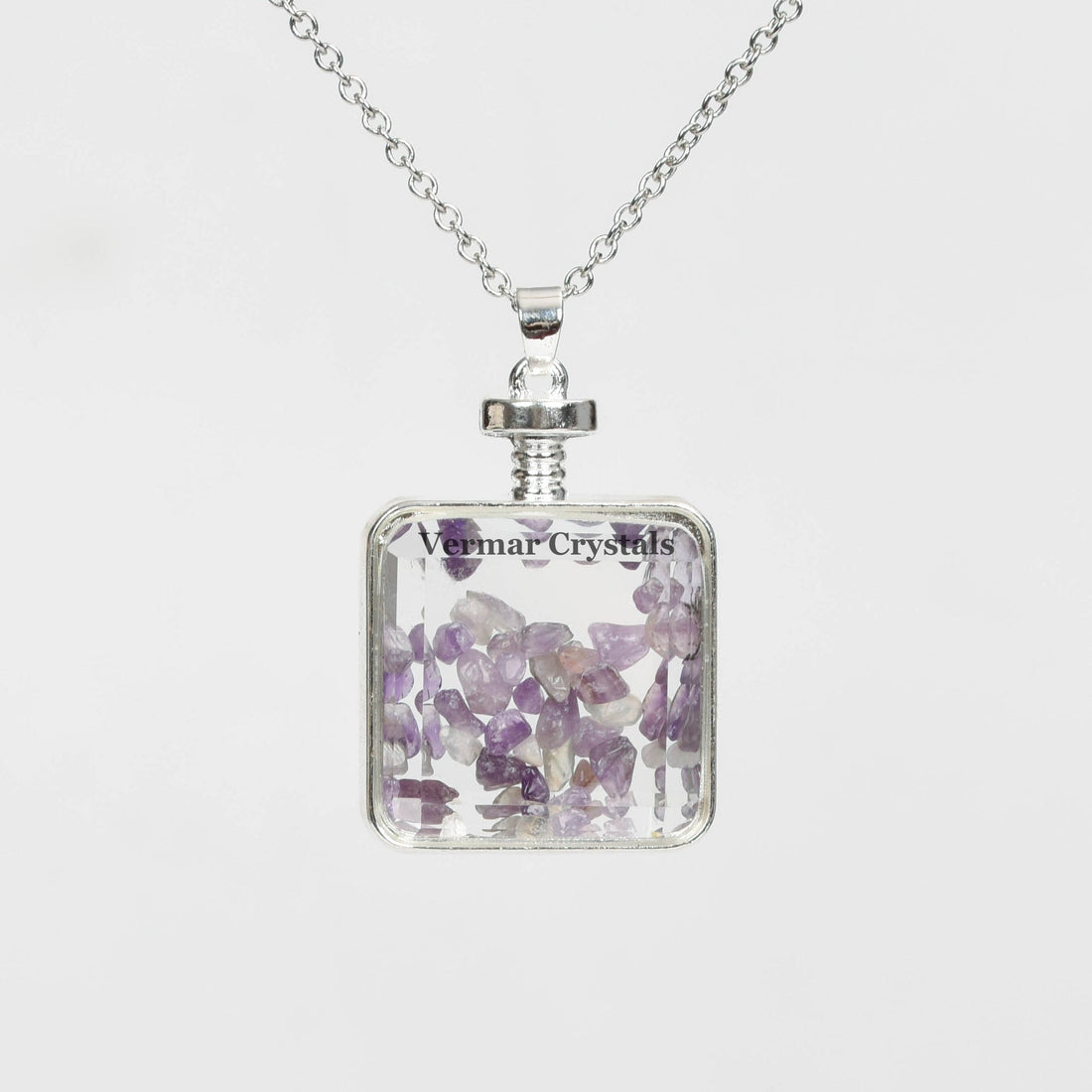 Handmade amethyst chip perfume bottle pendant with silver frame and delicate silver chain necklace on white background