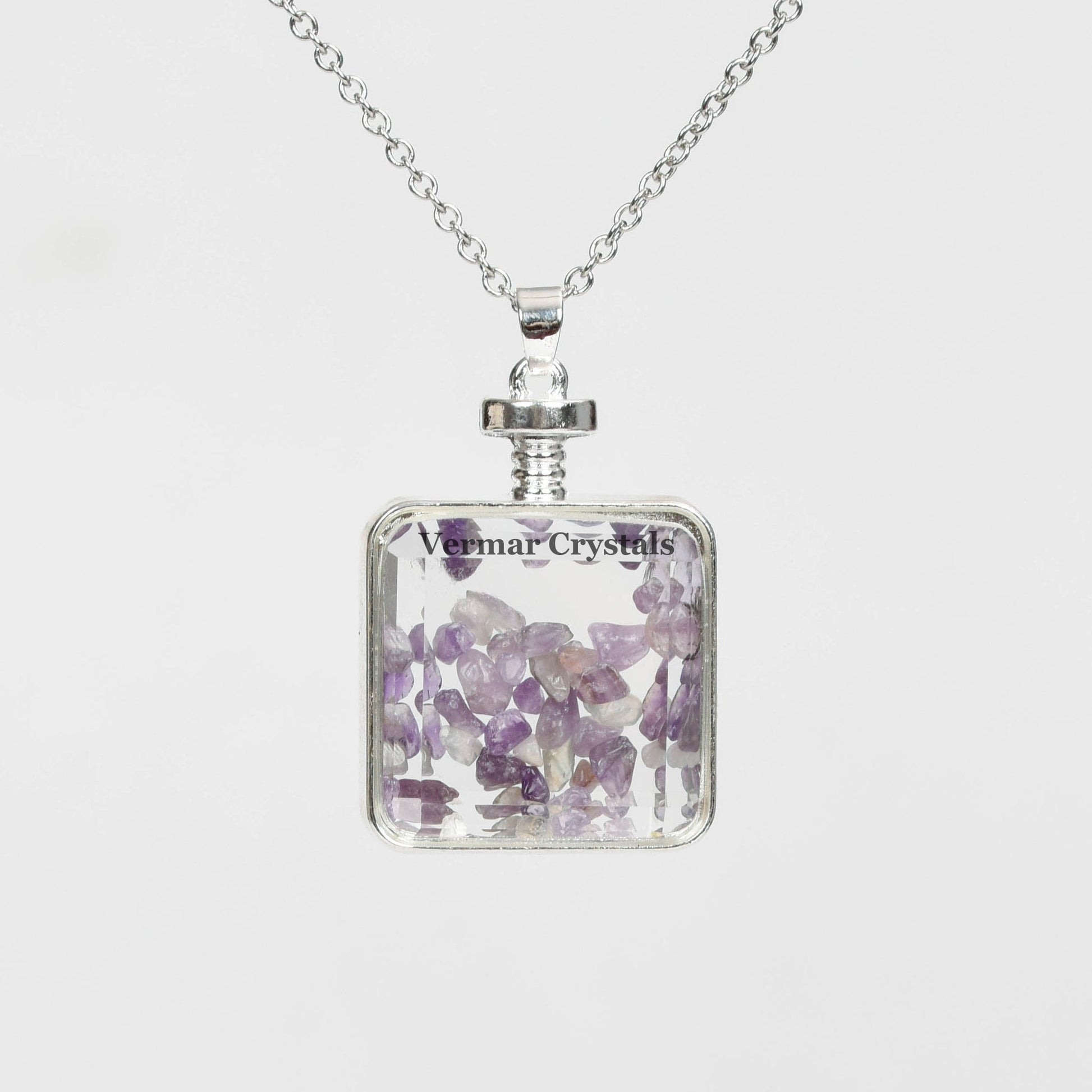 Handmade amethyst chip perfume bottle pendant with silver frame and delicate silver chain necklace on white background