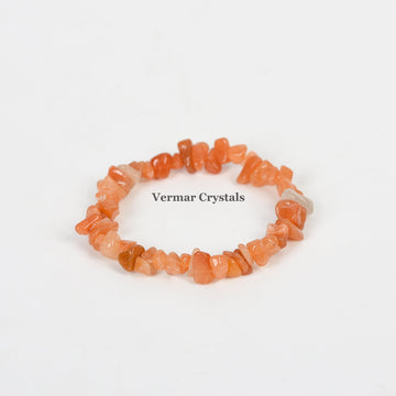 Handmade bracelet of irregular polished red aventurine chip stones arranged in a circular shape on white background
