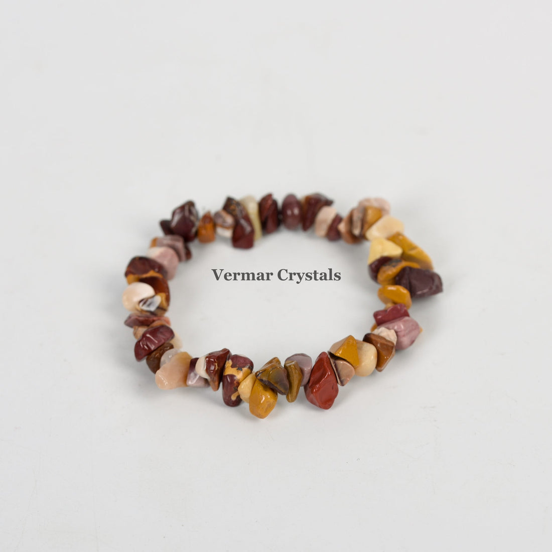 Stretchy bracelet made of irregular polished yellow, brown, and red jasper chip stones on a white background