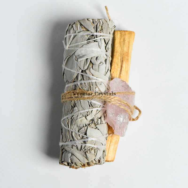 Bundle of Mexican white sage, palo santo stick, and raw rose quartz tied with twine for cleansing and healing rituals