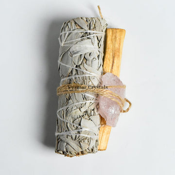 Bundle of Mexican white sage, palo santo stick, and raw rose quartz tied with twine for cleansing and healing rituals