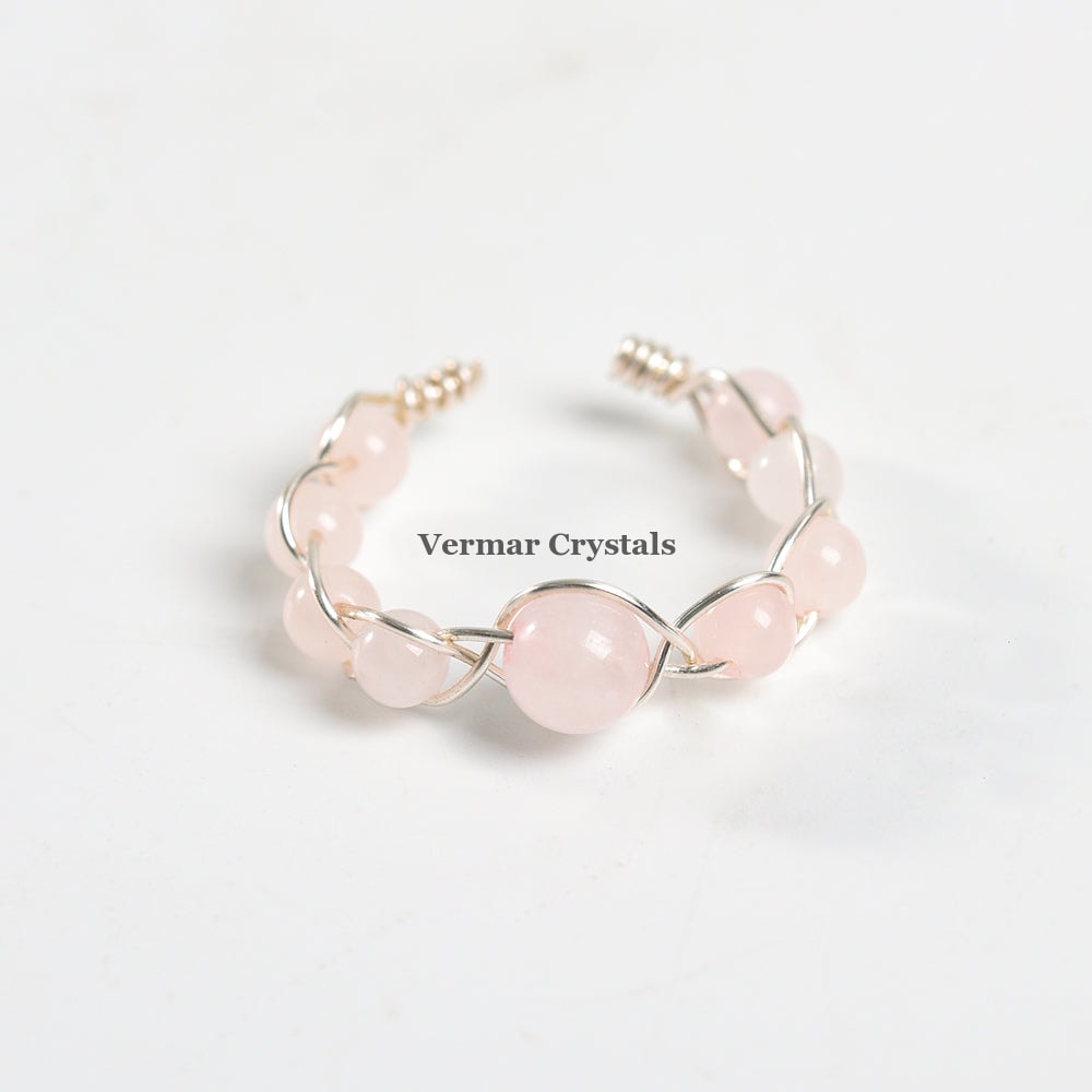 Handmade adjustable ring with polished rose quartz beads braided with silver wire on a white background
