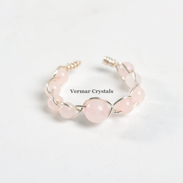 Handmade adjustable ring with polished rose quartz beads braided with silver wire on a white background