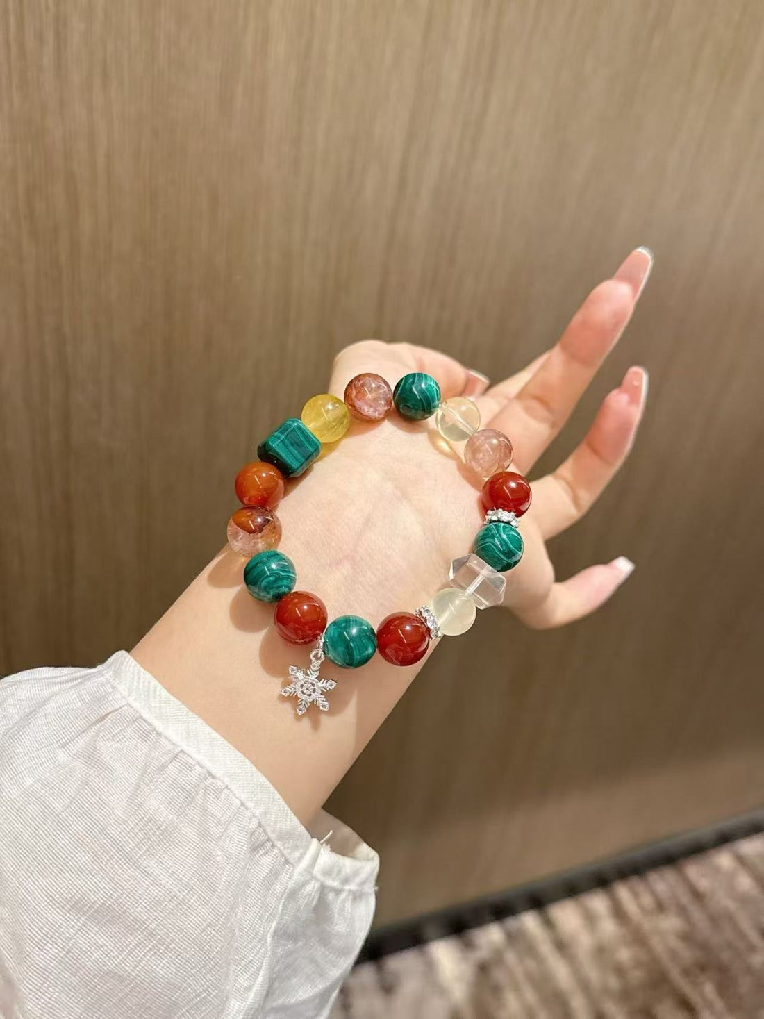 Christmas Harmony crystal bracelet with red, green, and clear 12mm beads on white cloth and held in hand